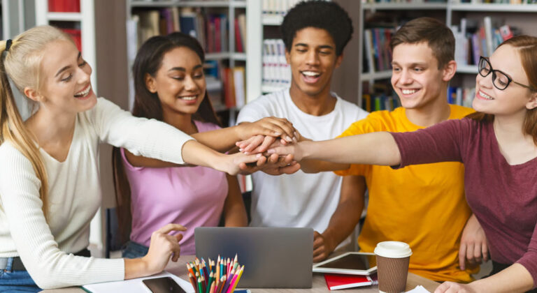 Schülergruppe-Team-reichen-sich-die-Hände