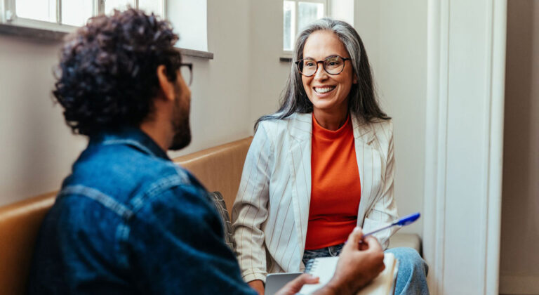Youmynd-Arsipa_shutterstock_2488933673_Gespräch_Coaching_Neeting_Notiz_Stift_Frau_Mann_Lachen